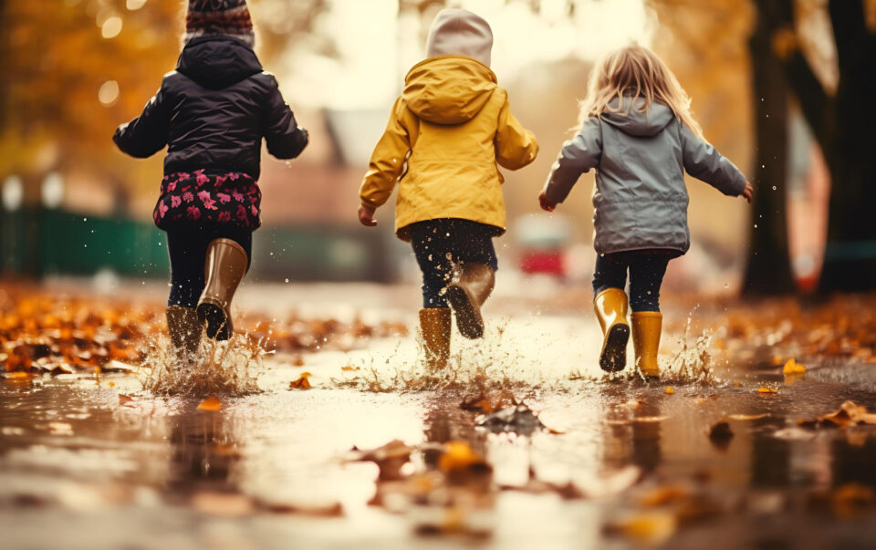 Children in autumn leaves and puddles wearing wellie boots